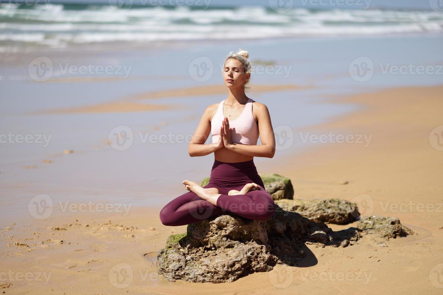 donna bionda caucasica che pratica yoga in spiaggia foto