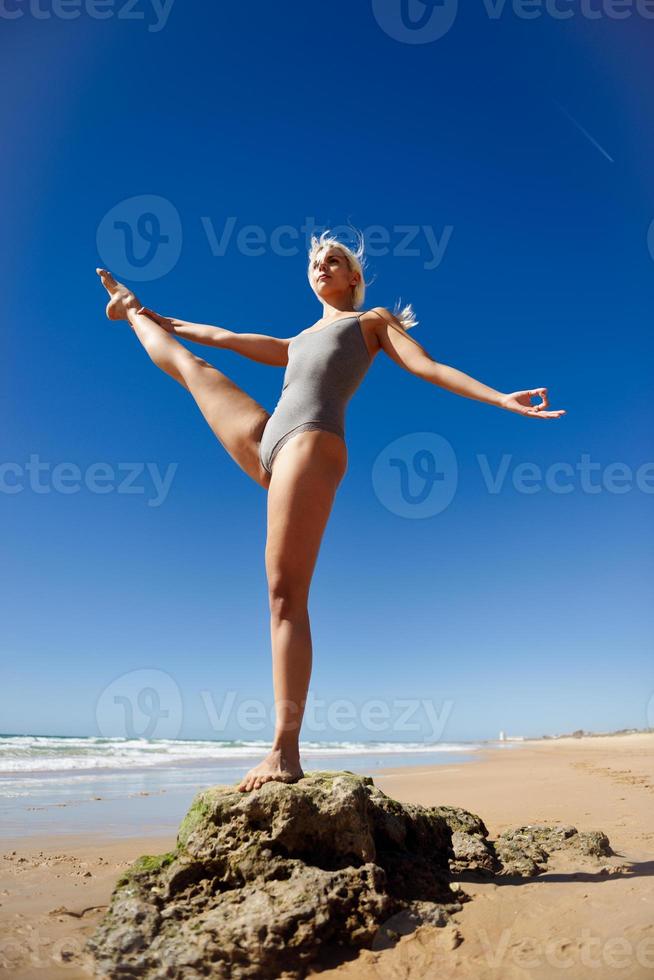 donna bionda caucasica che pratica yoga in spiaggia foto