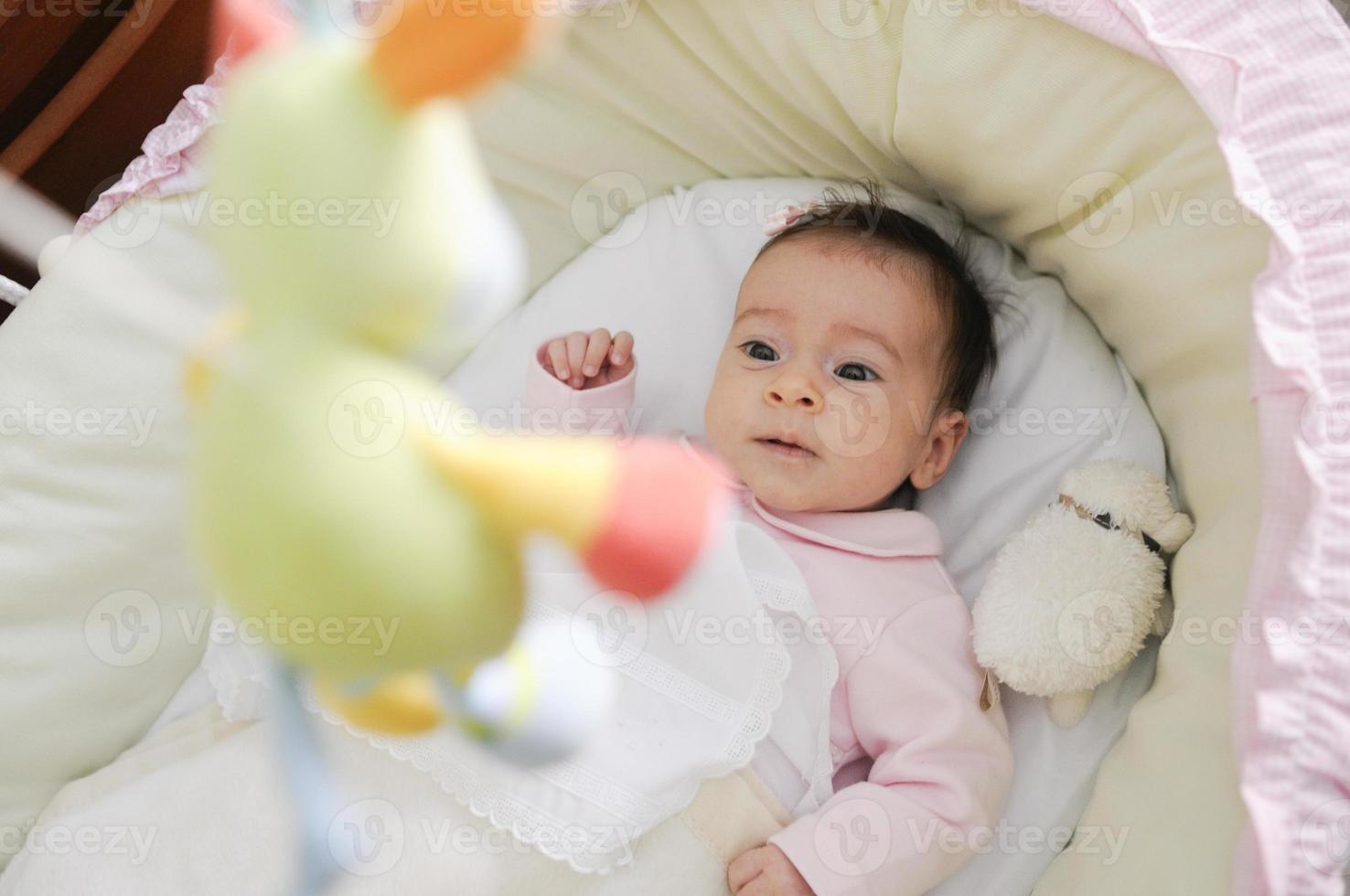 bambina che guarda una bambola nella sua culla foto