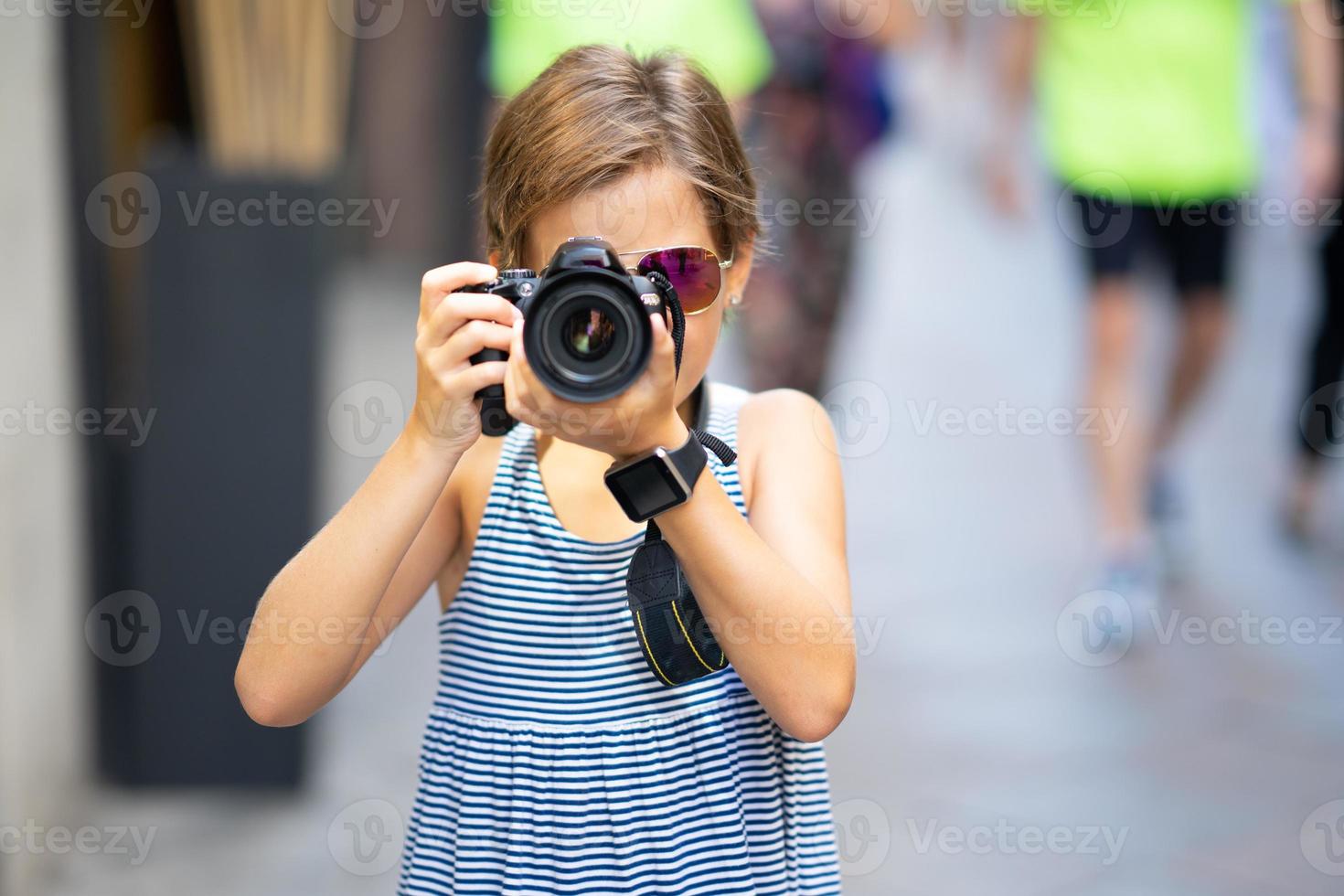 bambina che fa foto con la fotocamera reflex digitale sulla strada della città