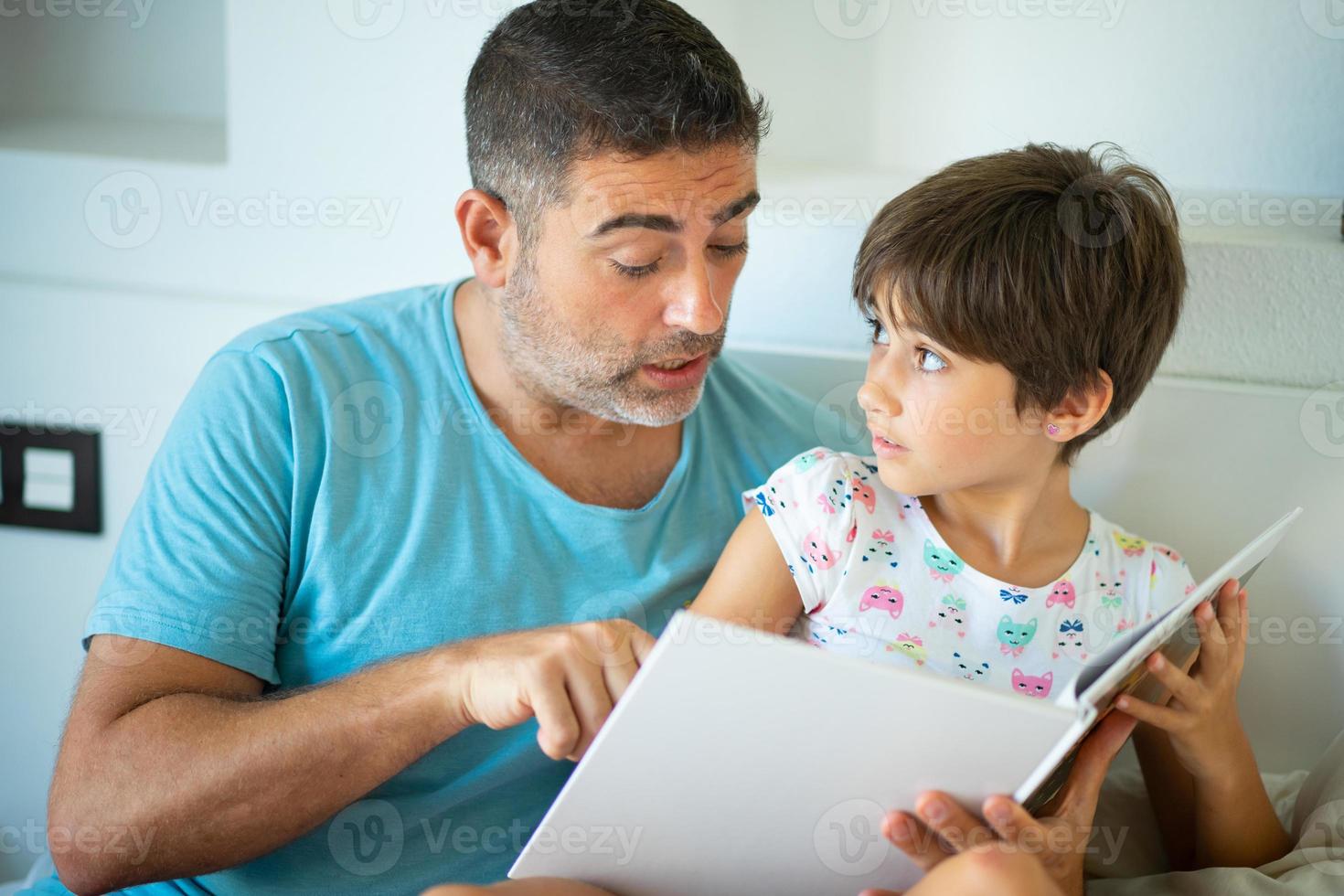 padre di mezza età con sua figlia di otto anni che utilizza tablet digitale in camera da letto. foto