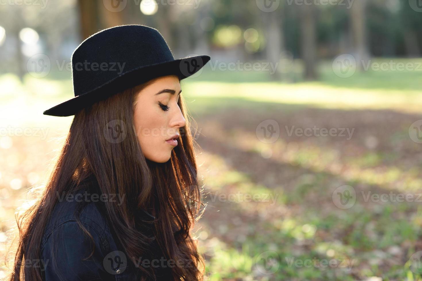 donna premurosa seduta da sola all'aperto con indosso un cappello foto