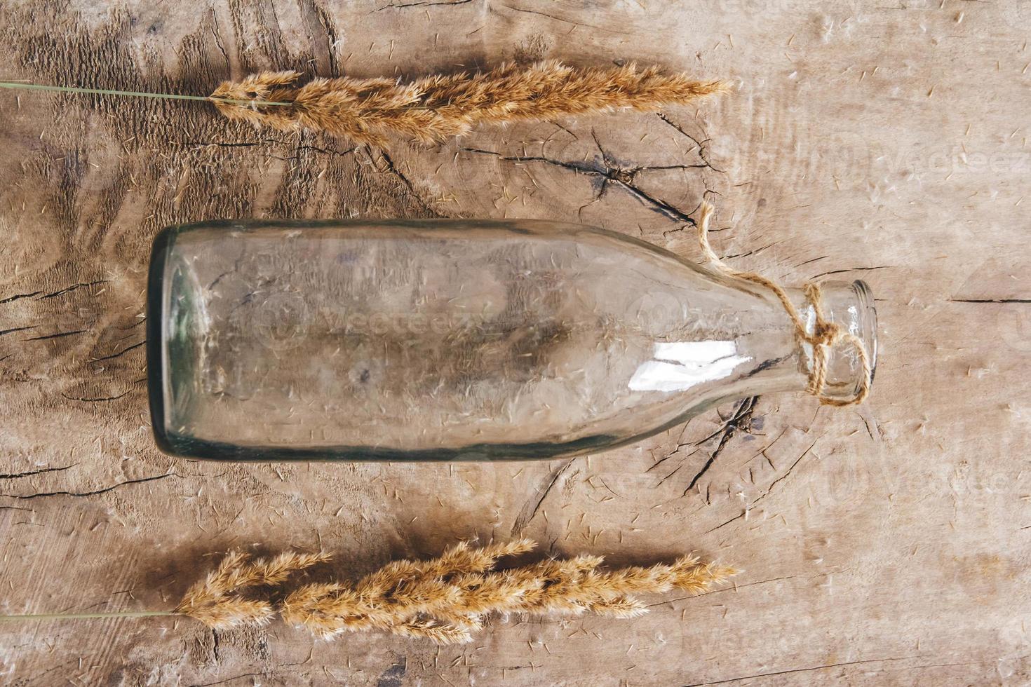 natura morta di un mazzo di fiori secchi in una bottiglia di vetro su un tavolo di legno foto