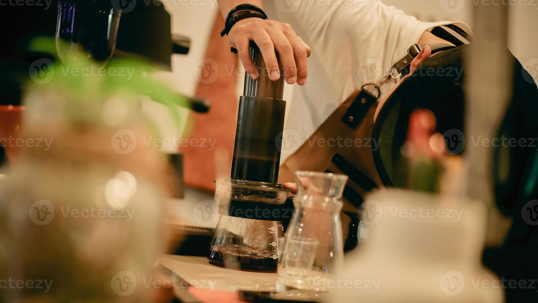 un barista maschio che prepara il caffè con il metodo aeropress foto