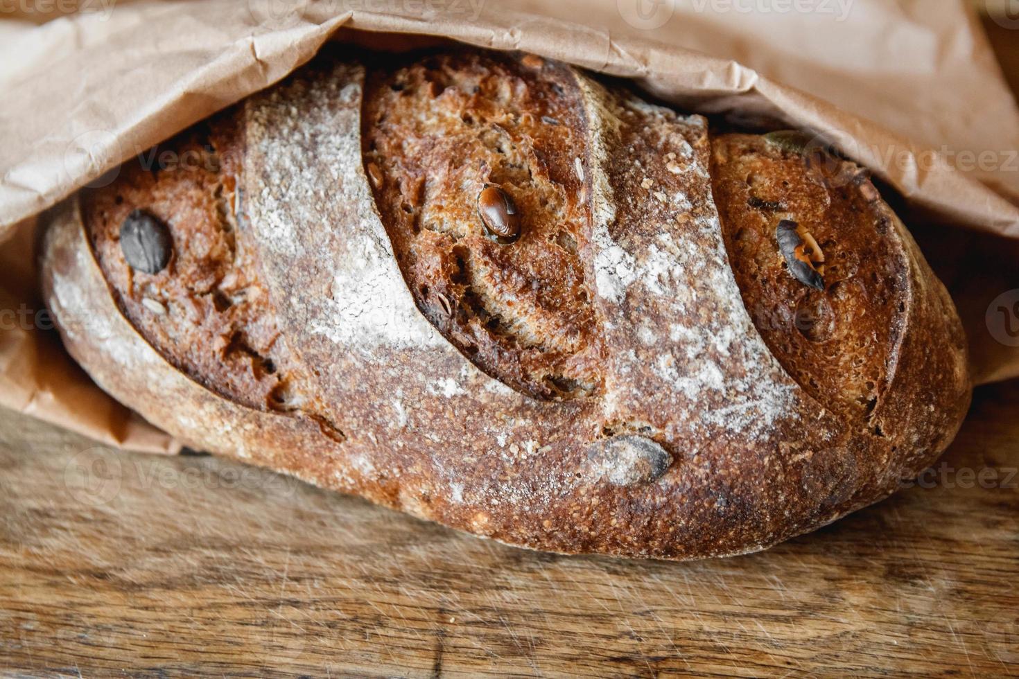 pane fresco marrone con semi su fondo di legno vecchio foto