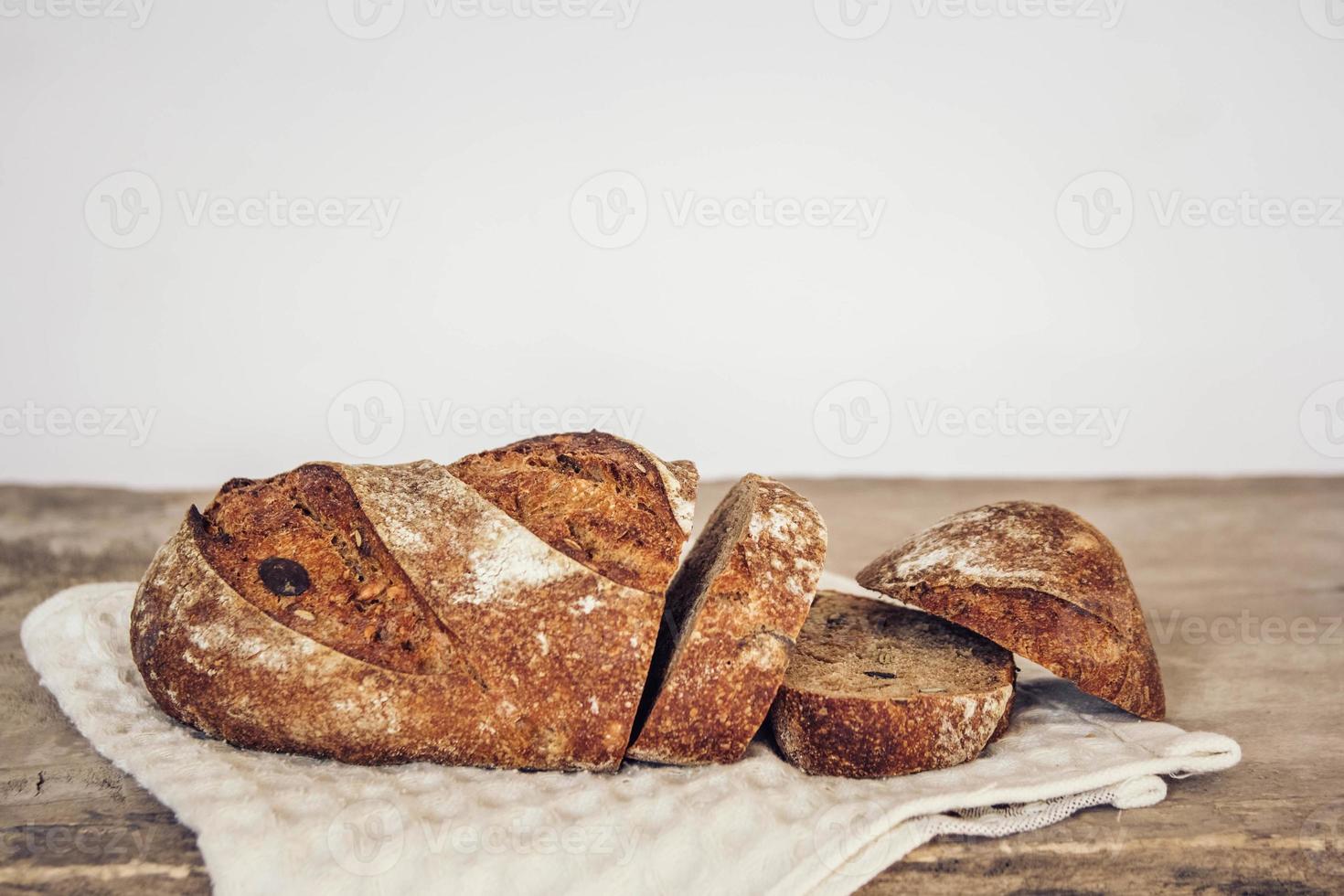 il pane fresco marrone con i semi viene tagliato a pezzi su uno sfondo di legno vecchio foto