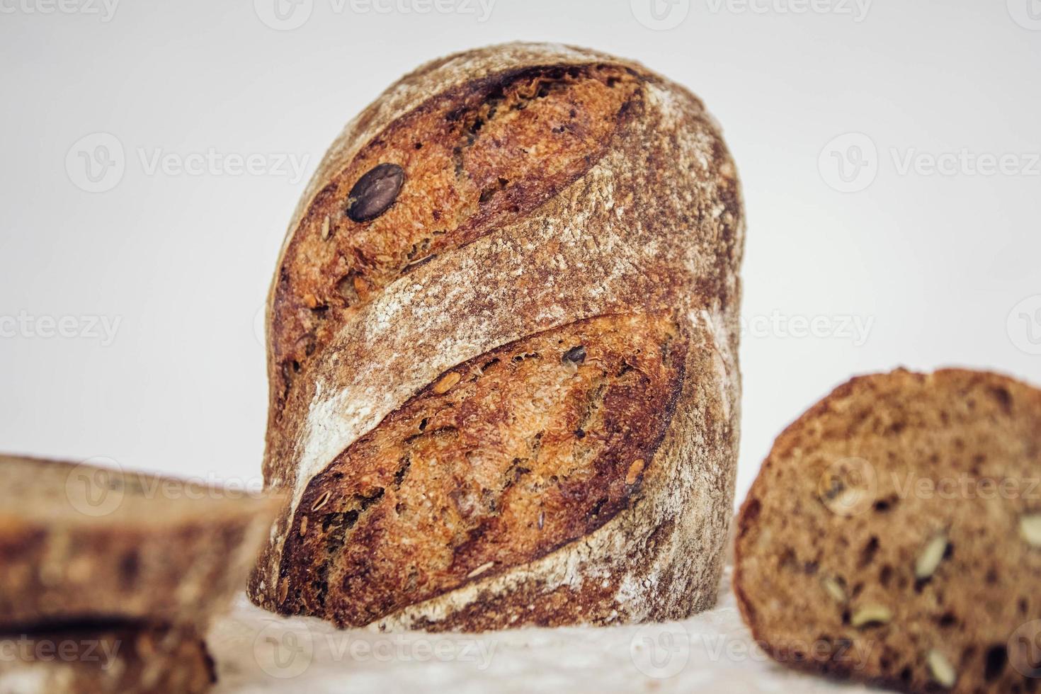 il pane fresco marrone con i semi viene tagliato a pezzi su uno sfondo di legno vecchio foto