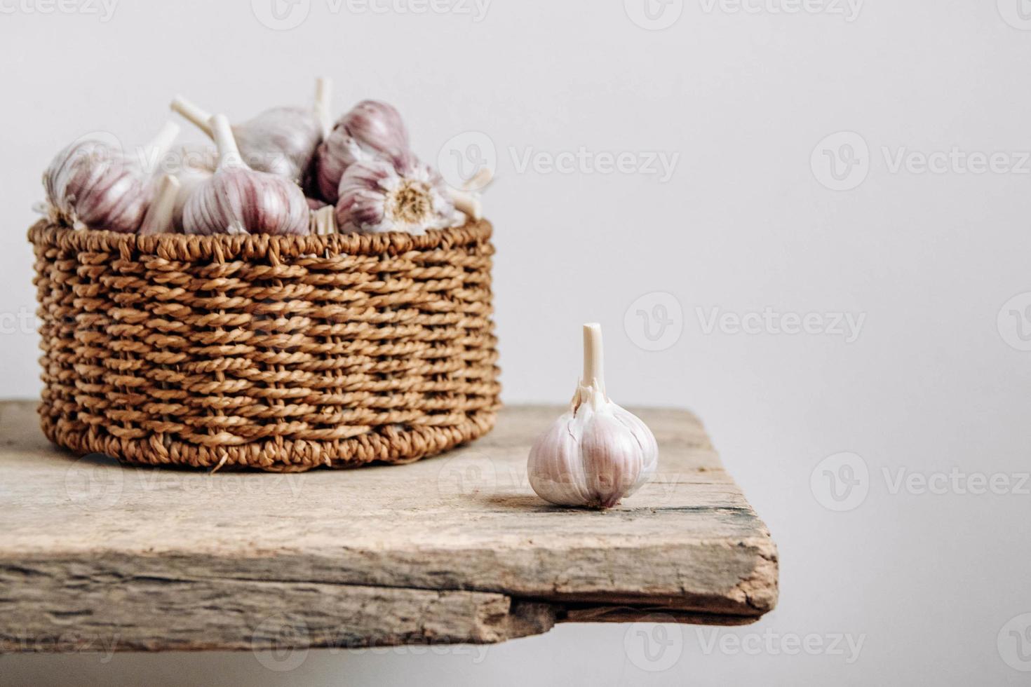 aglio in un cesto di vimini su uno sfondo di tavolo in legno foto