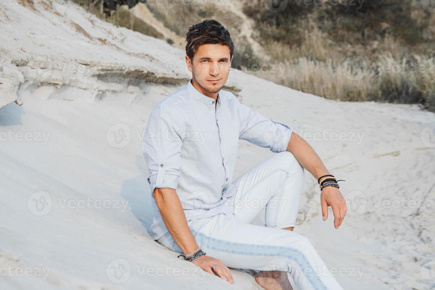 uomo in abiti leggeri siede nel deserto foto