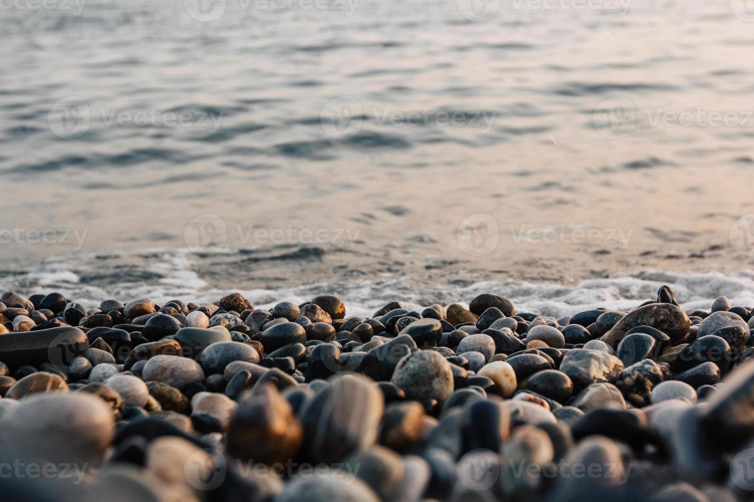 piccole pietre in riva al mare con effetto bokeh. sfondo decorativo sfocato, posto per il testo foto