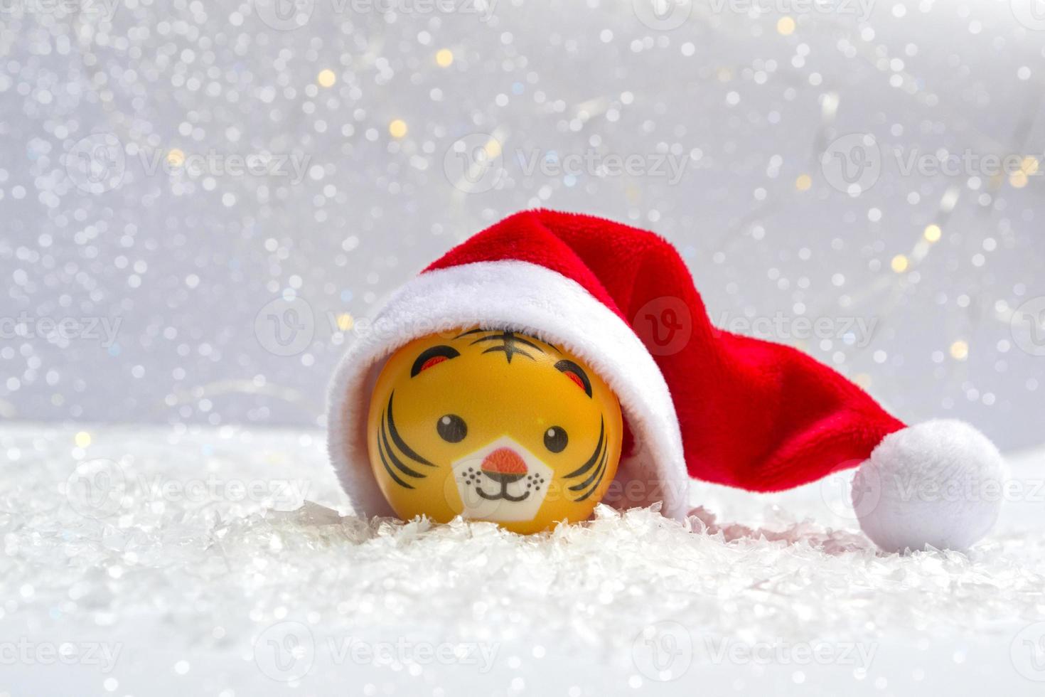 il simbolo del nuovo anno è una tigre con un cappello da Babbo Natale sulla neve su uno sfondo di luci bokeh. primo piano del nuovo anno foto