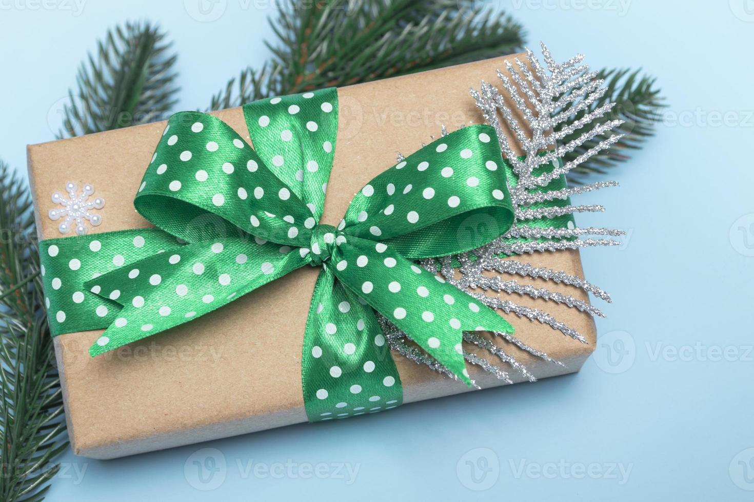 buon Natale e Felice Anno nuovo. regalo con un nastro verde a pois e ornamenti su sfondo blu. primo piano dello spazio della copia della carta di auguri foto