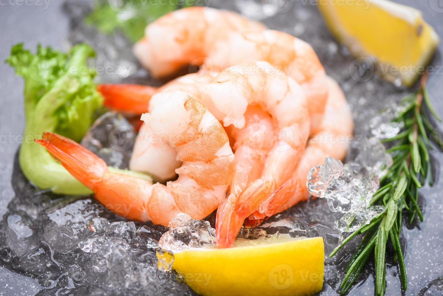 gamberi bolliti gamberi su ghiaccio congelati al ristorante di pesce - gamberi freschi su piatto scuro con limone rosmarino ingredienti erbe e spezie per cucinare frutti di mare foto