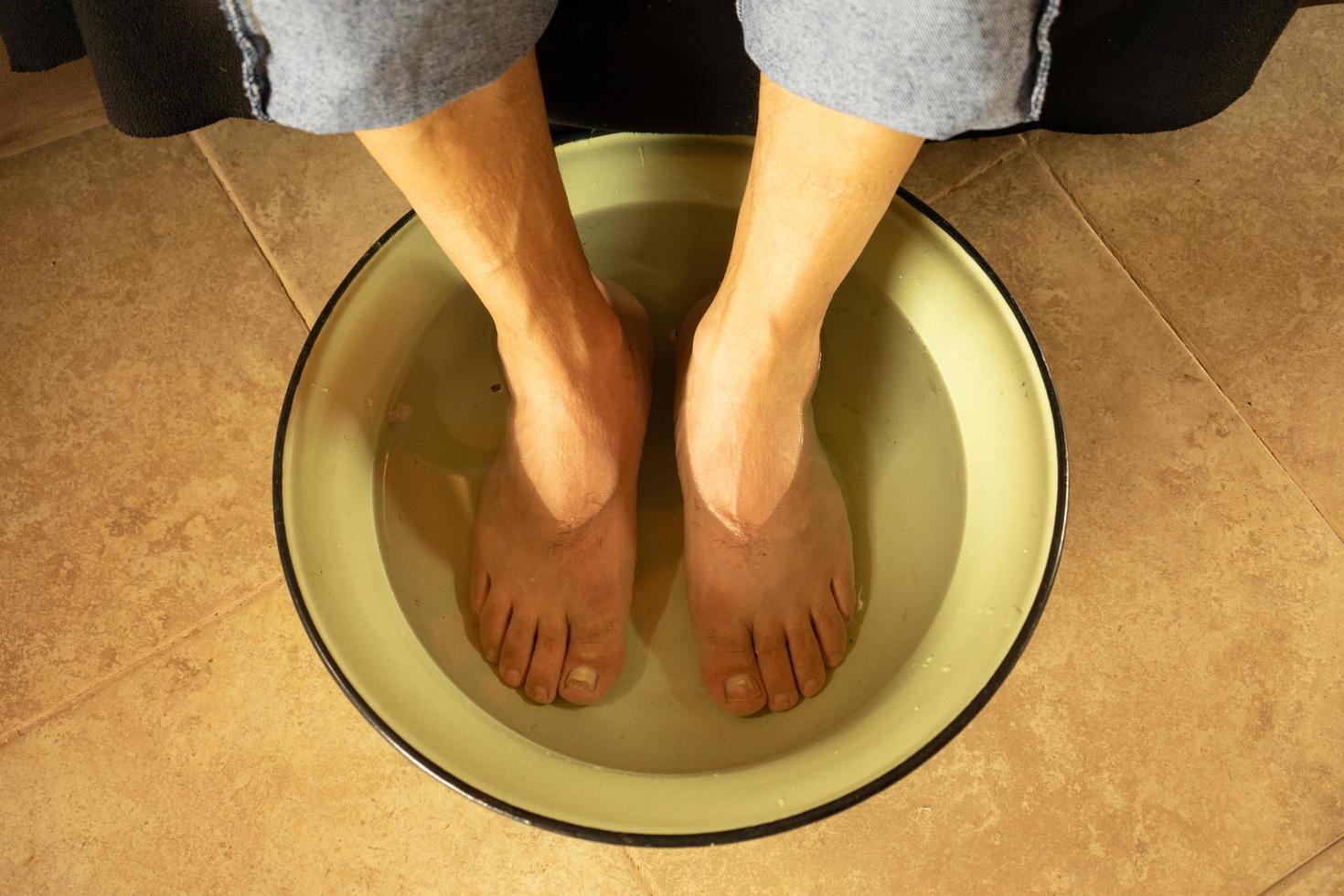 un uomo con i piedi in una ciotola di acqua calda foto