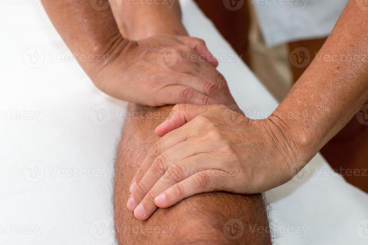 massaggiatore che massaggia la gamba di un uomo sotto il ginocchio foto