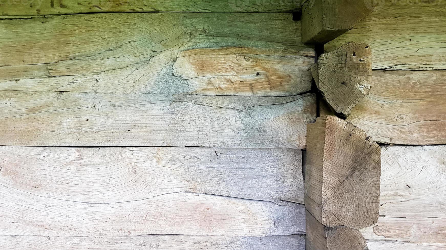 parete, facciata, angolo di una casa di tronchi di pino piallato in legno nel villaggio. una priorità bassa di struttura di legno rustico marrone. architettura. Edificio verde foto