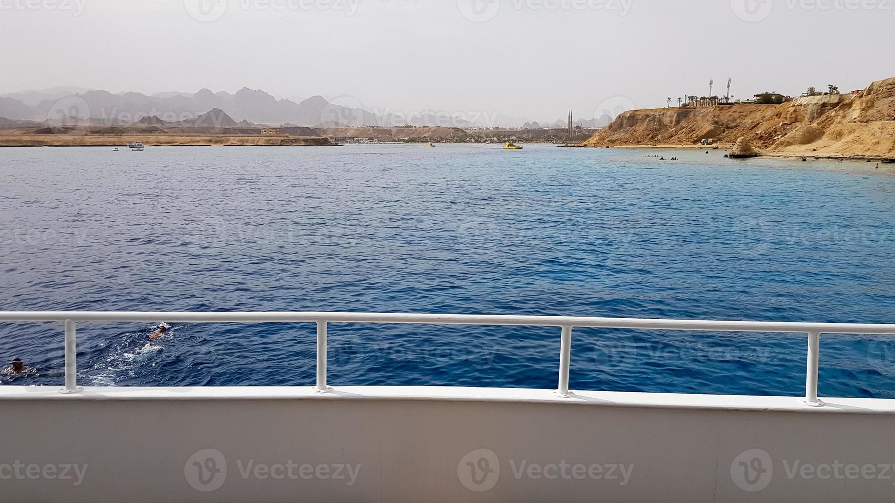 bella vista dal ponte di una nave da crociera nel mar rosso in egitto. paesaggio della costa rocciosa egiziana con uno yacht. parte della nave sullo sfondo del deserto e del mare. foto