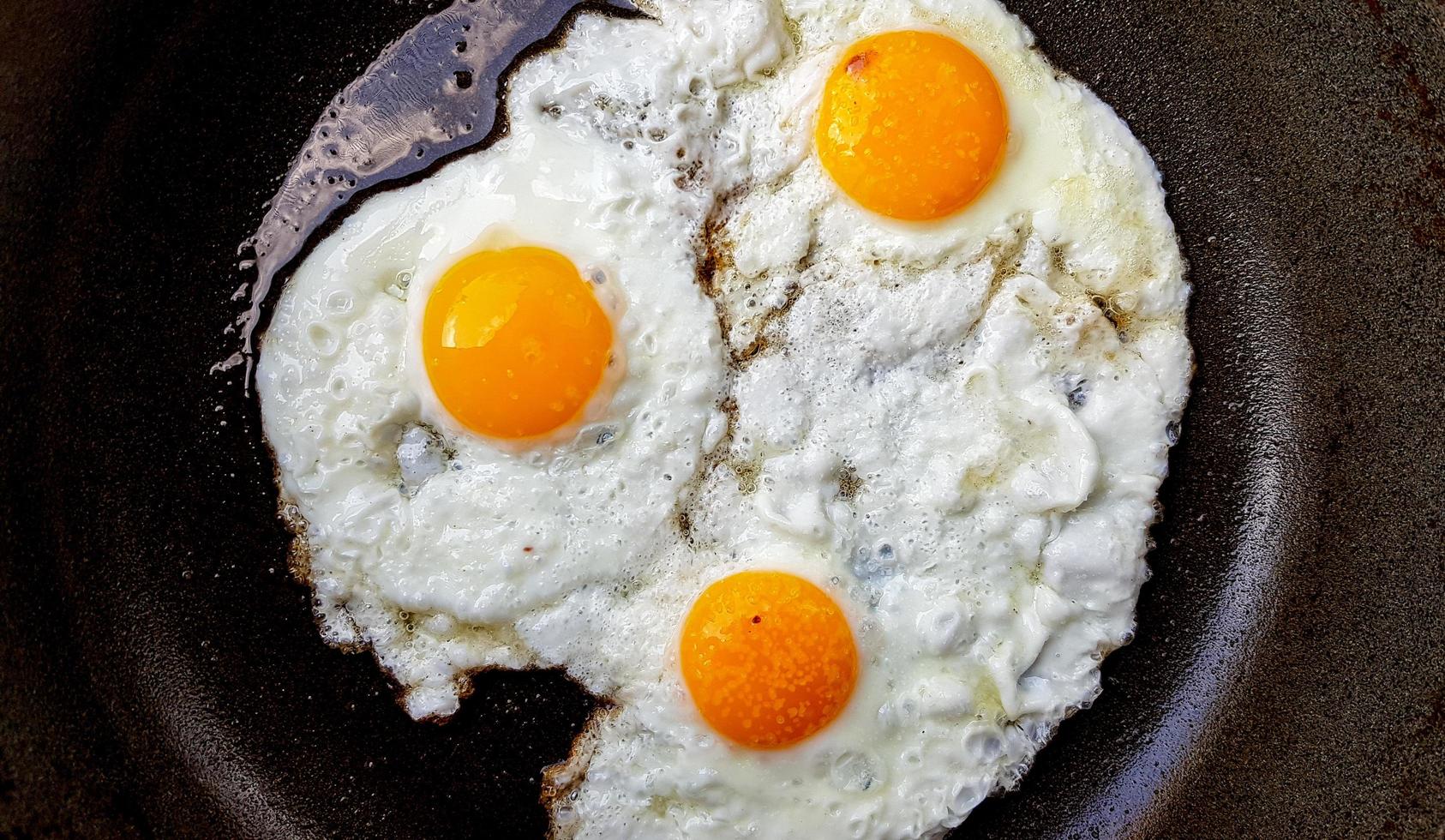 tre uova fritte ruspanti in una padella antiaderente calda foto