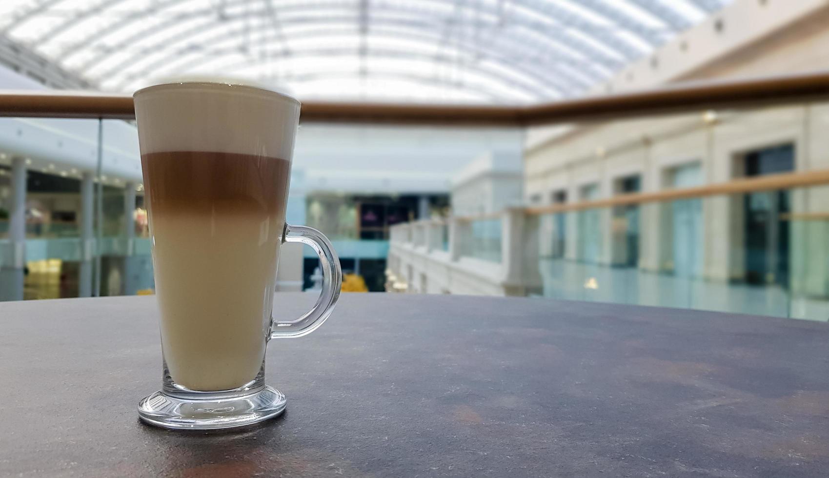 classico caffè latte macchiato in una tazza di vetro sul tavolo. tazza di vetro con bevanda calda. foto