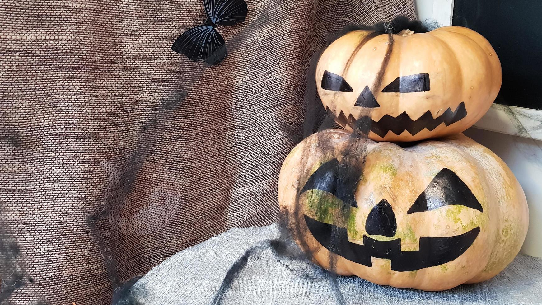 zucca con una faccia spaventosa su un tavolo di legno. l'interno della casa è decorato con zucche e ragnatele per la festa di halloween. foto