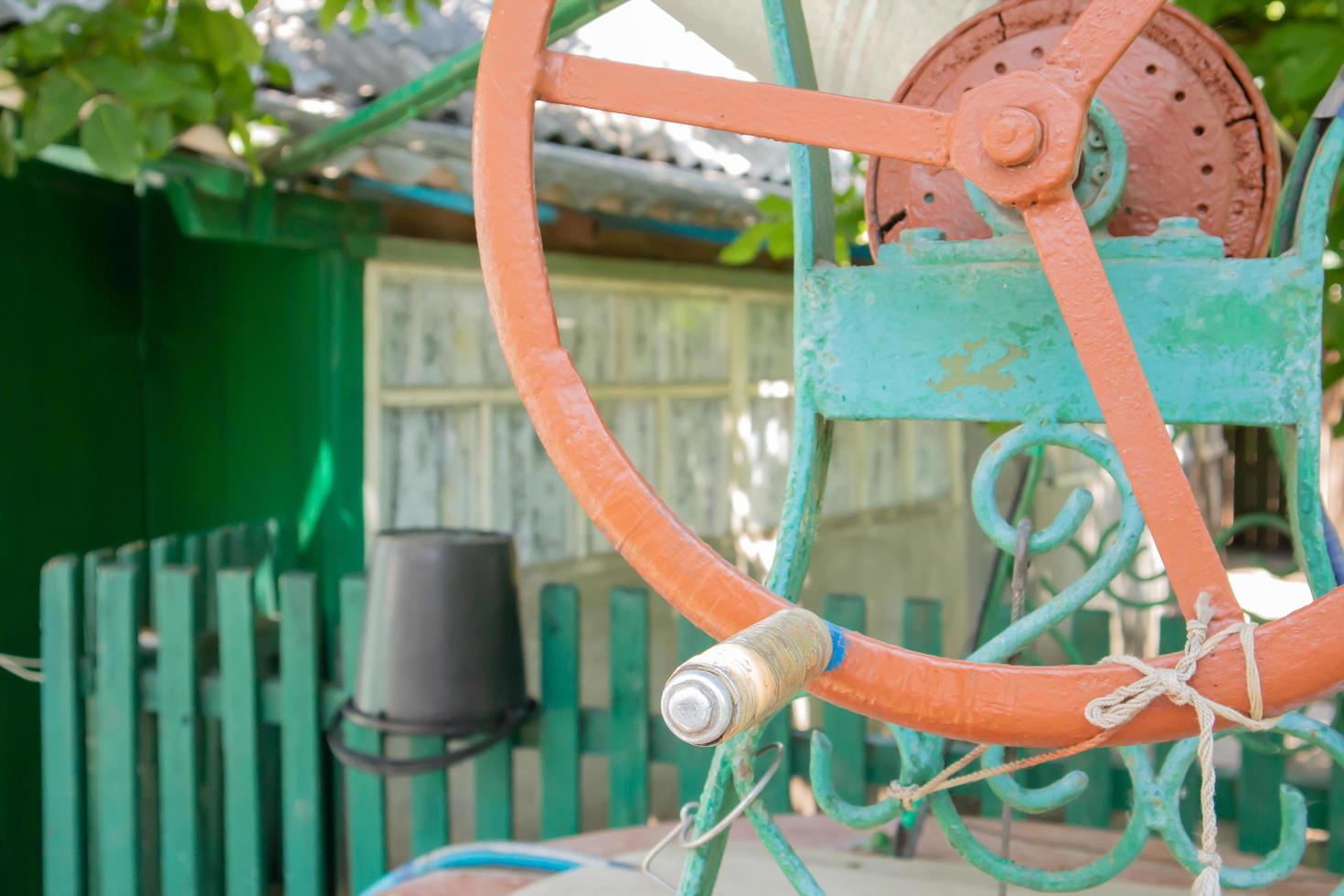 un vecchio pozzo d'acqua con un secchio in giardino, una maniglia in metallo per sollevare l'acqua da terra. villaggio bene sotto il tetto con una corda. retrò bene in campagna. foto