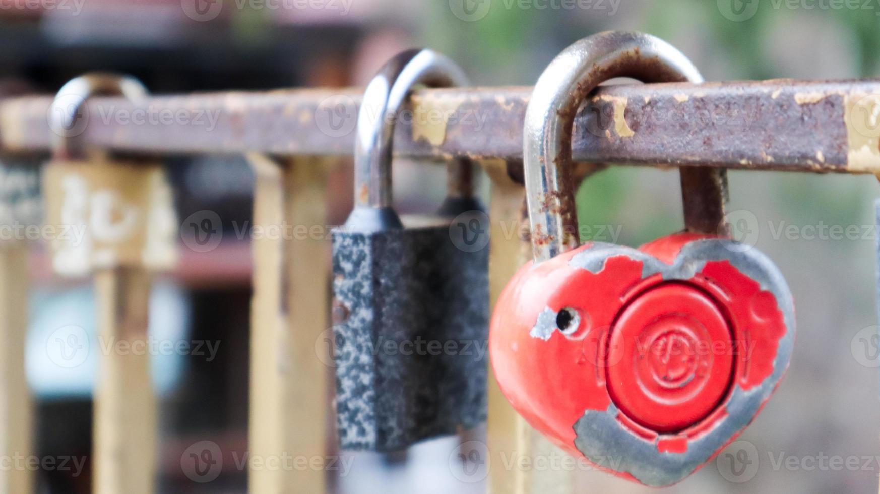 lucchetto rosso malandato a forma di cuore. concetto di amore di San Valentino. un lucchetto appeso a una ringhiera di metallo è un segno di amore eterno. la tradizione di agganciare un castello con una staccionata foto