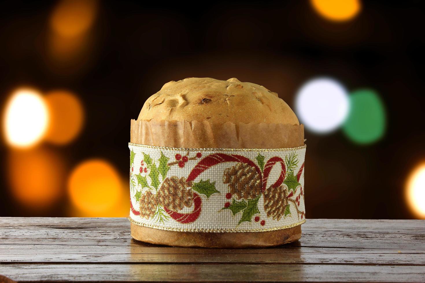 panettone, cibo decorativo, su tavola di legno, luci sfocate sullo sfondo foto