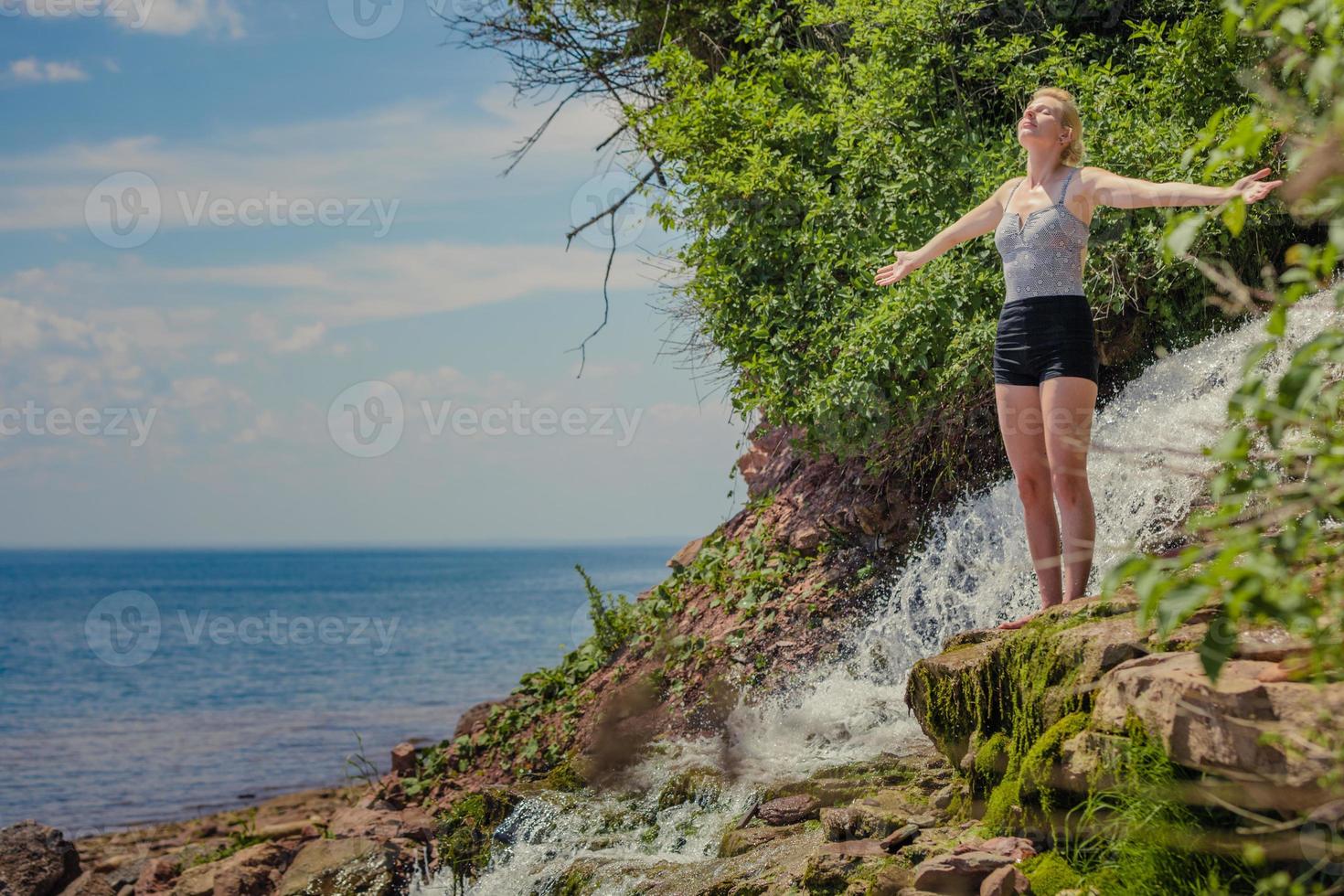 giovane donna che fa posizione yoga vicino a una cascata foto