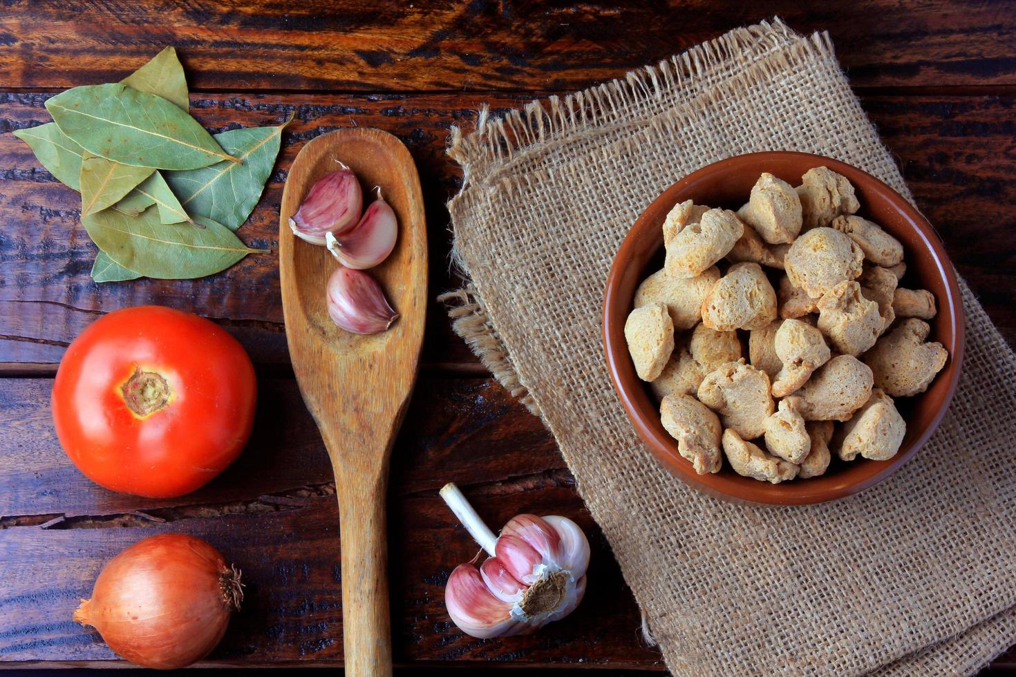 carne di soia, pezzi in una ciotola di ceramica marrone. pezzi di semi di soia crudi su fondo di legno rustico foto