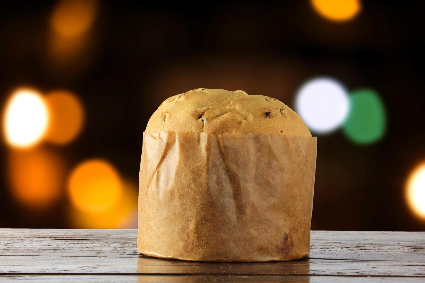 panettone, cibo decorativo, su tavola di legno, luci sfocate sullo sfondo foto