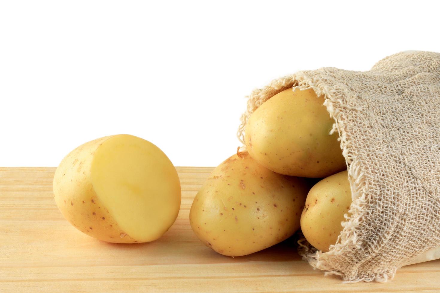 patata che fuoriesce dal sacco sul tavolo di legno, patate tagliate foto
