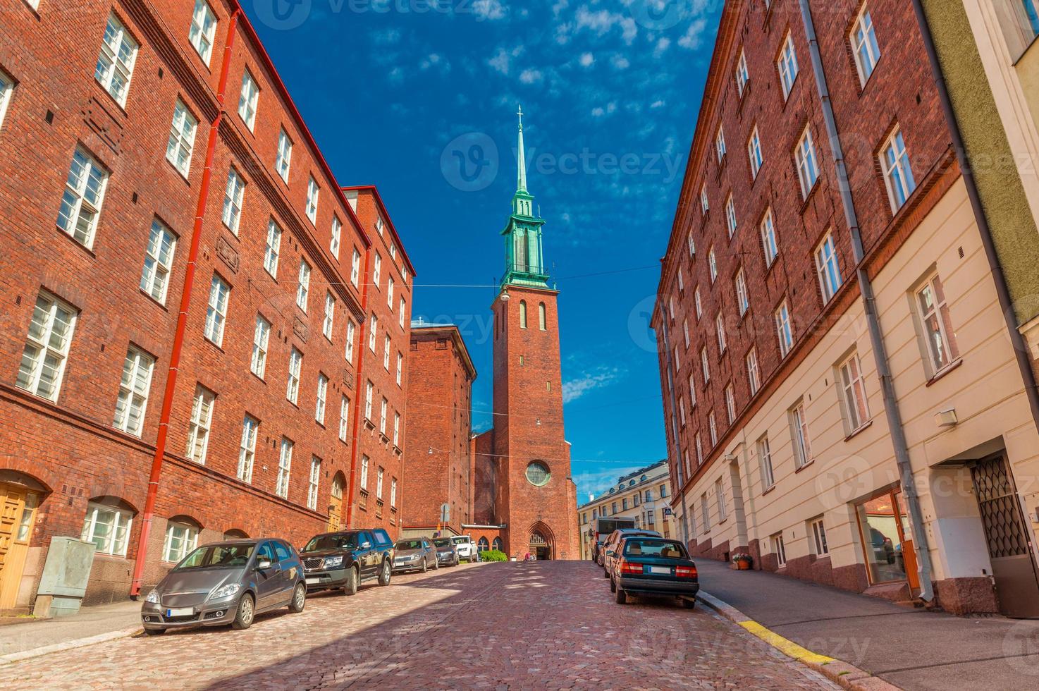 una strada di helsinki con l'architettura tradizionale e una chiesa kristuskyrkan, in stile neogotico finlandese foto