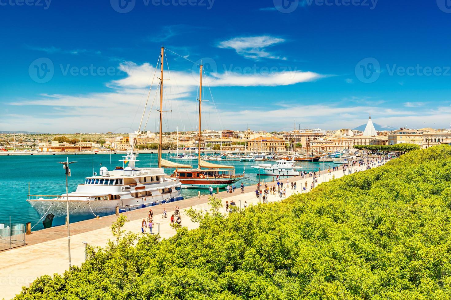 bellissima vista sul porto di siracusa con gente che passeggia sul lungomare. paesaggio urbano dell'isola di ortigia, sicilia, italia foto