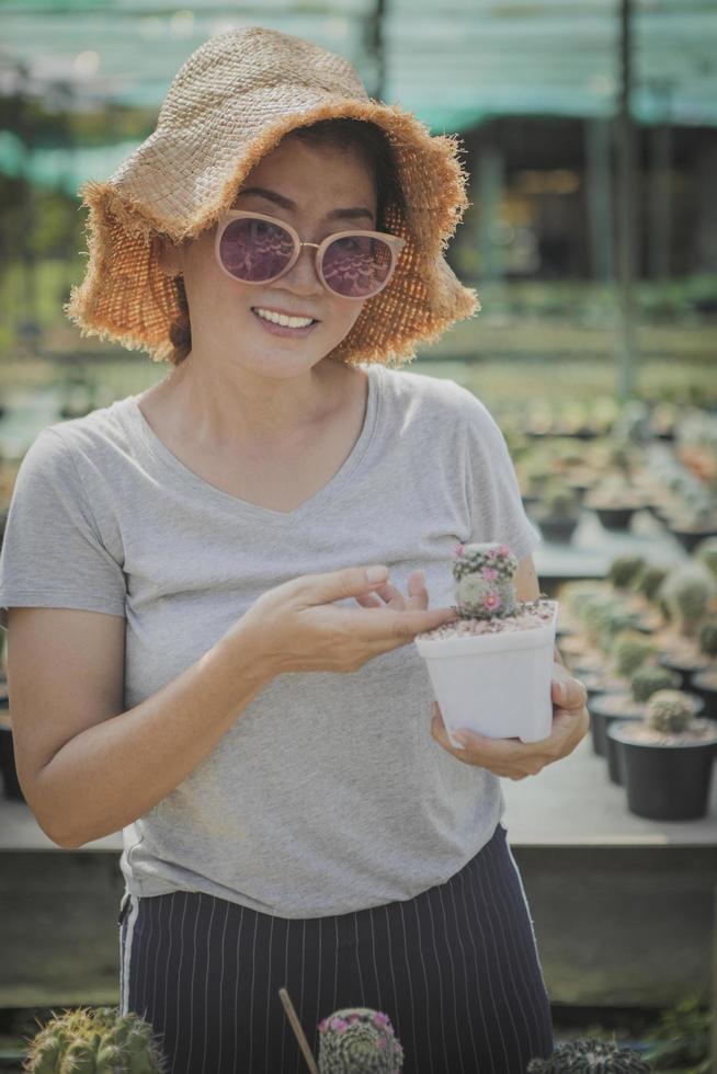 donna sorridente a trentadue denti che tiene in mano un vaso di cactus foto