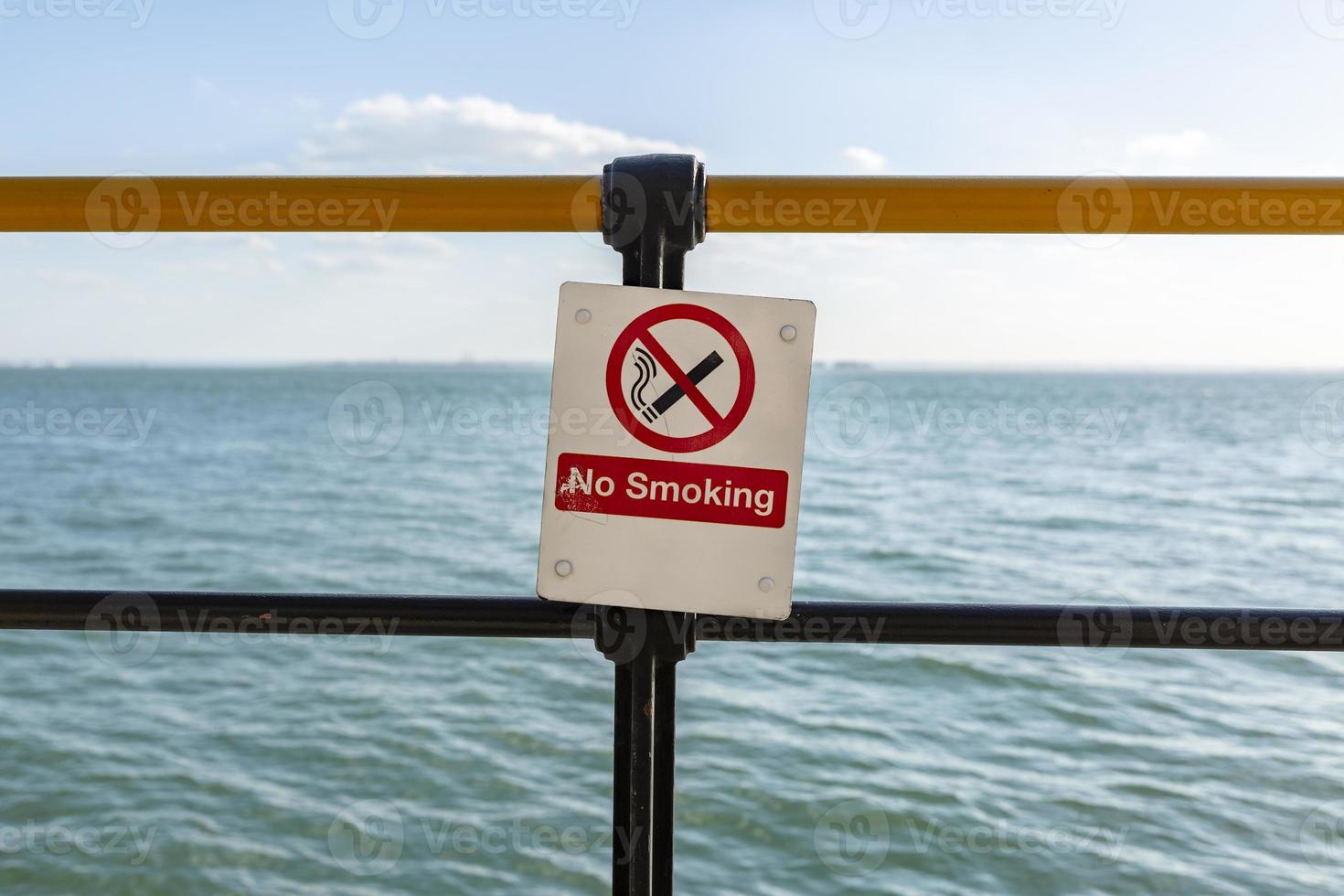 Segnale di pericolo non fumatori di fronte al mare blu. foto