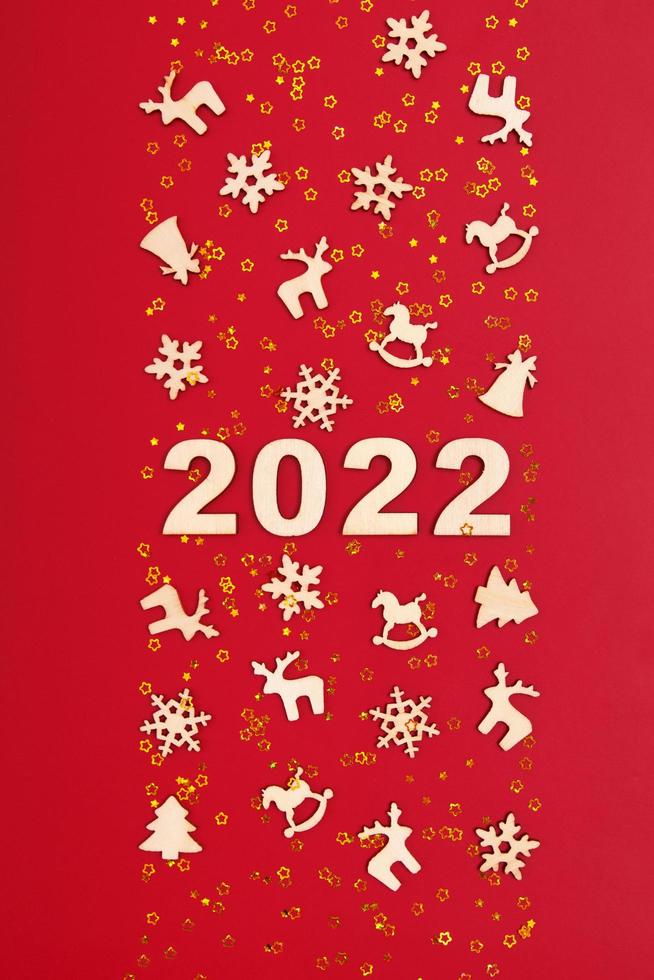 felice anno nuovo 2022 numeri su sfondo rosso con stelle dorate e decorazioni natalizie in legno foto
