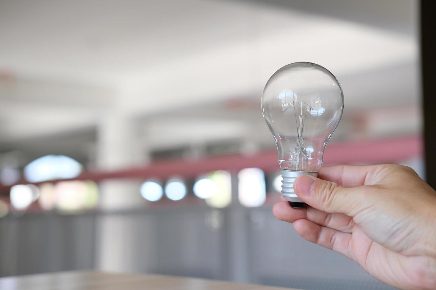 mano che tiene una lampadina su un tavolo, nozione di idea creatività e ispirazione, tecnologie future foto