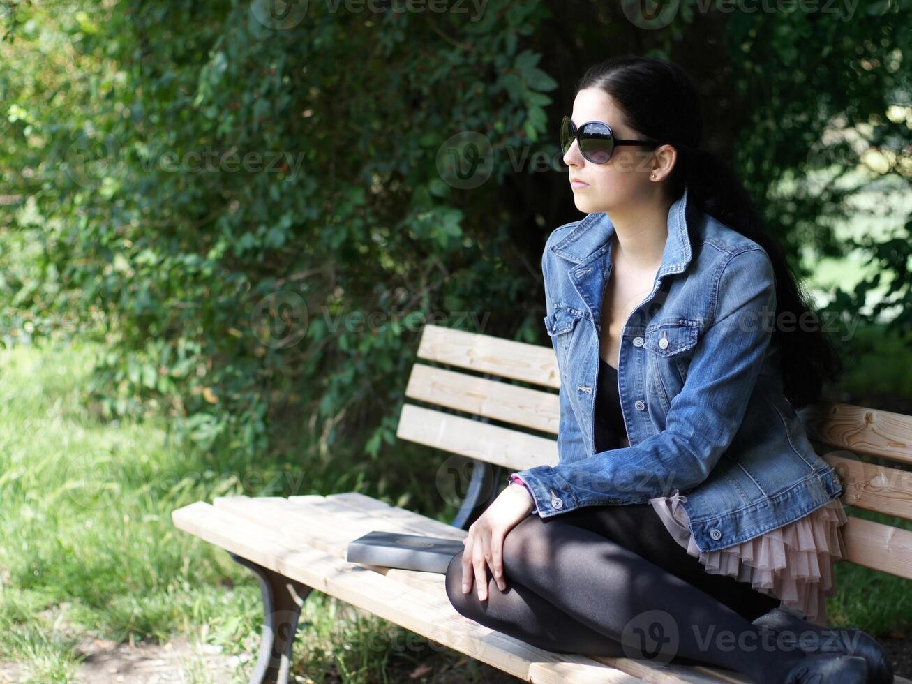 ragazza con occhiali da sole rilassante su parco panchina foto