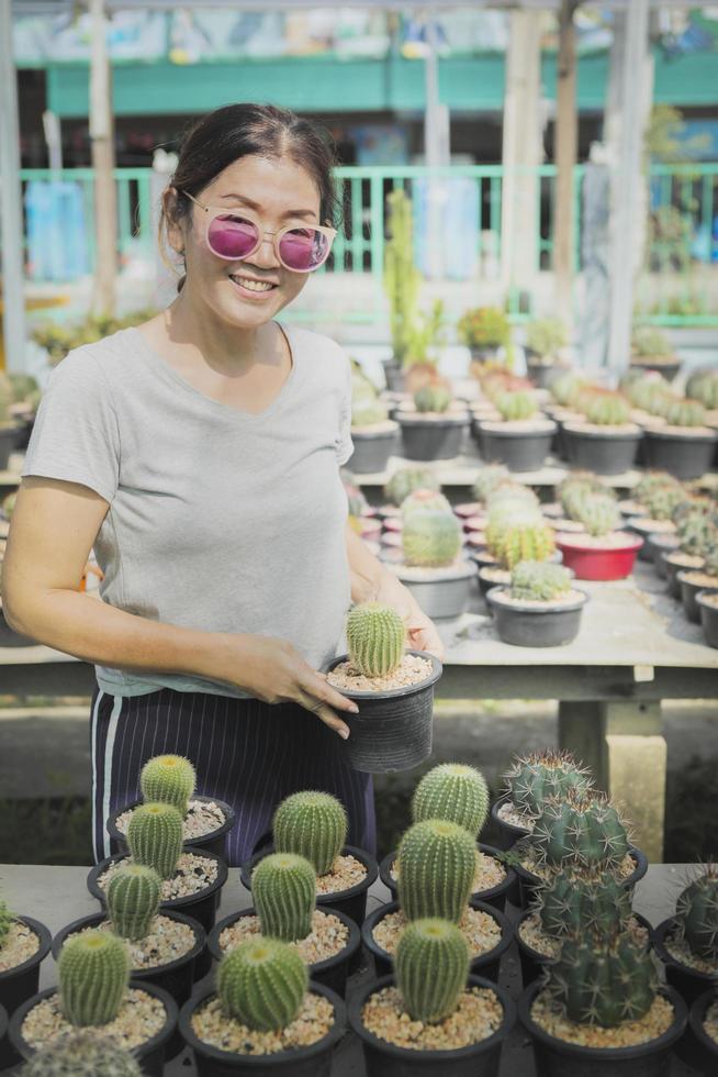 donna a trentadue denti che sorride con felicità tenendo in mano un vaso di cactus foto