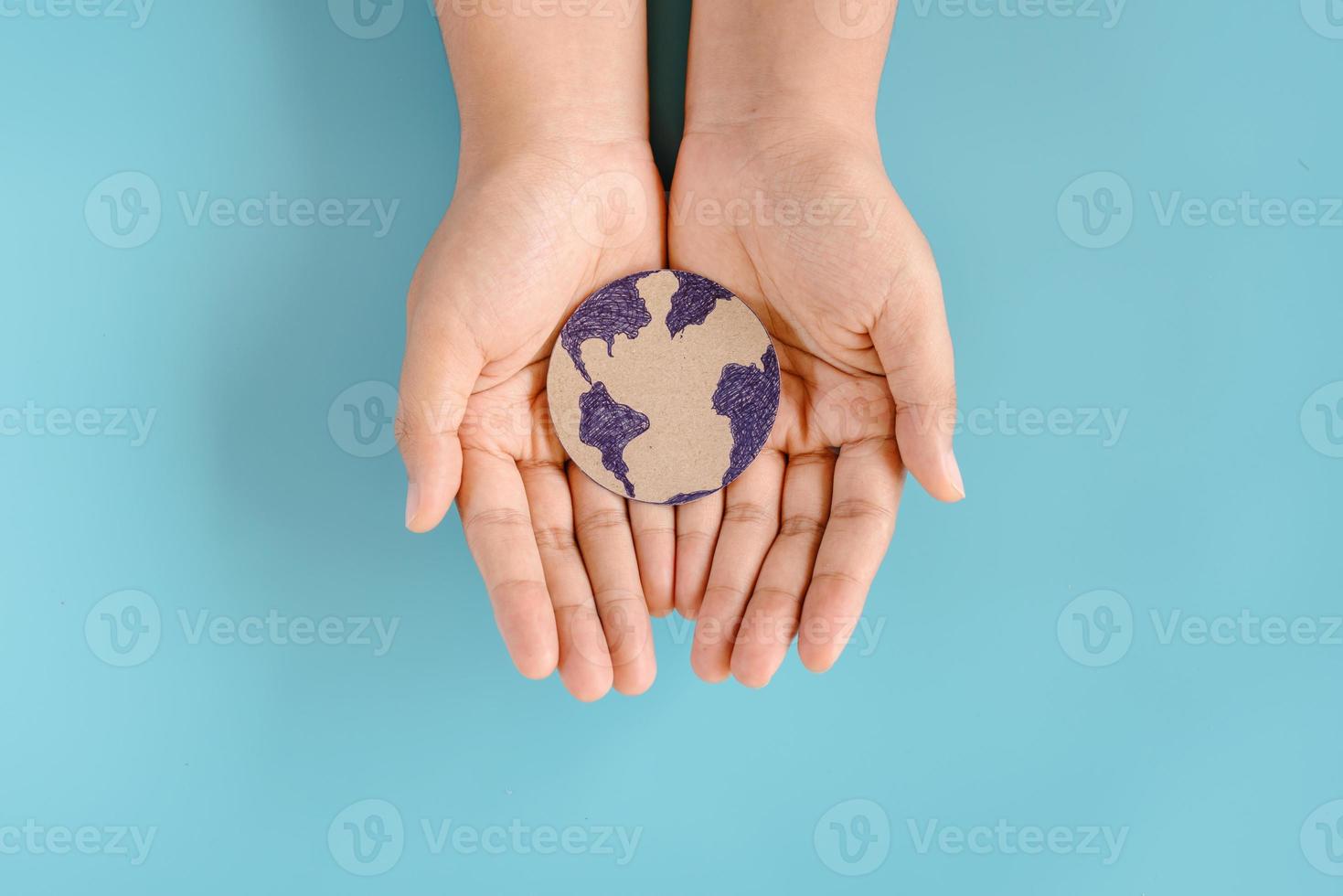 salvare la terra e il concetto di cambiamento climatico, proteggere il pianeta terra per risorse sostenibili. mani femminili che tengono il simbolo del globo su sfondo blu isolato. protezione della terra per una vita sostenibile foto