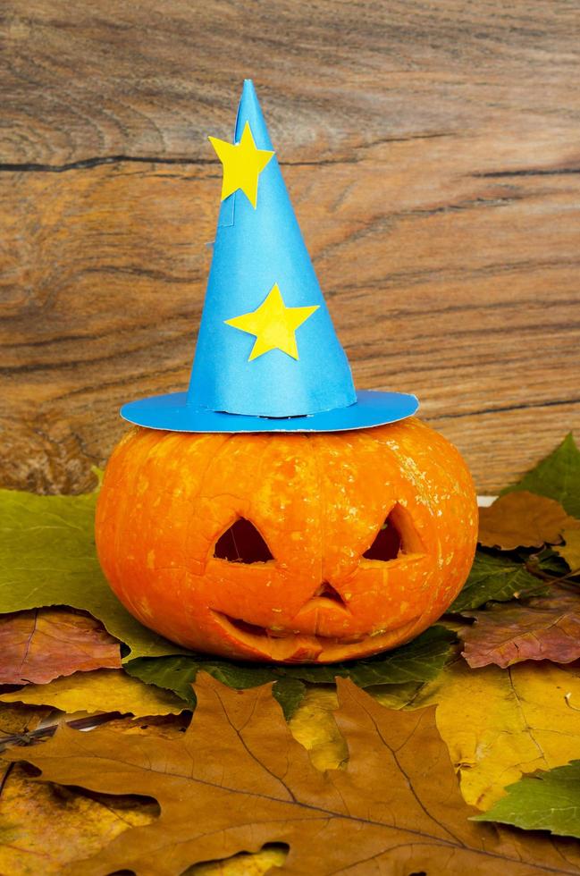 divertente zucca arancione su sfondo di foglie autunnali per halloween foto