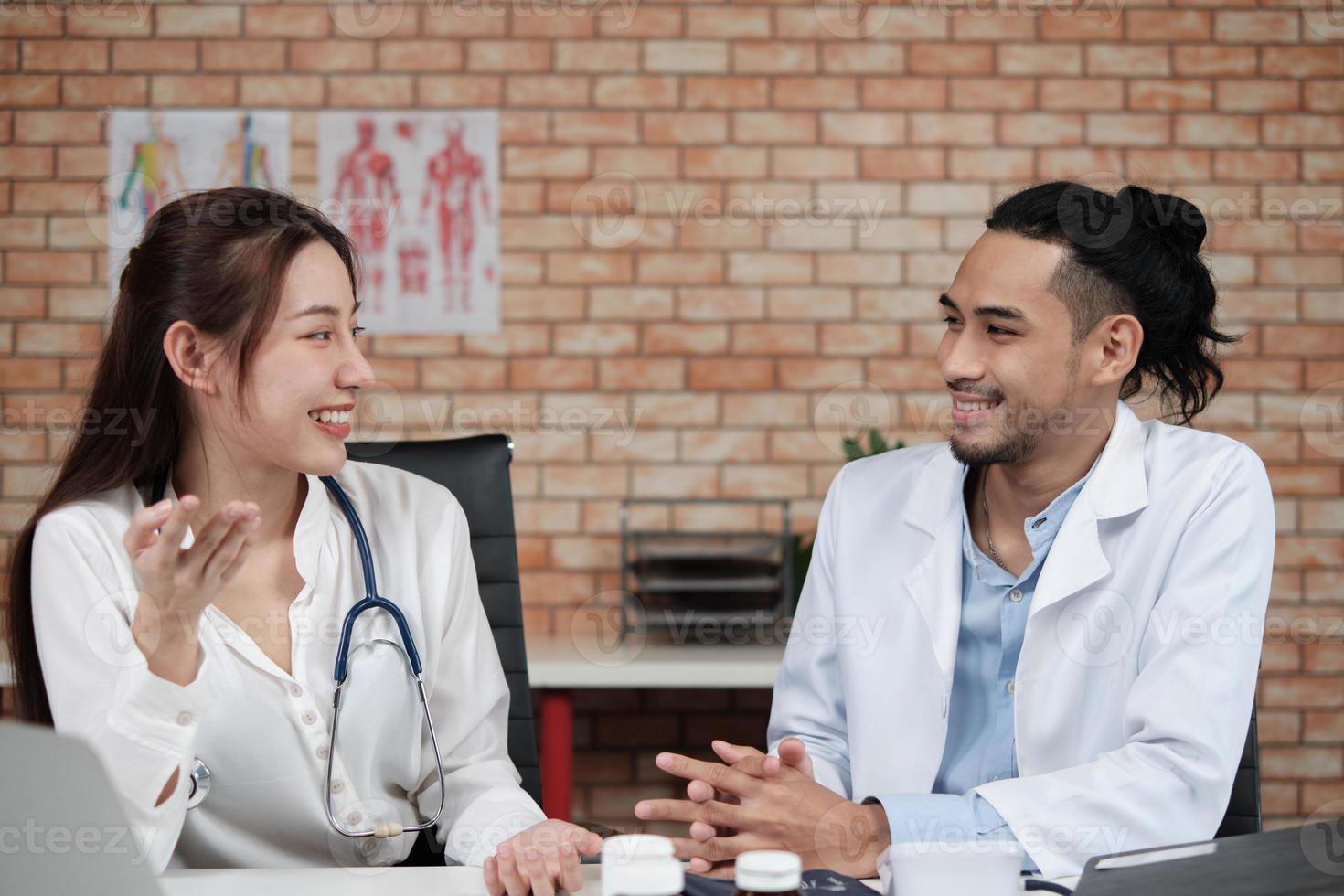 partner del team sanitario. due giovani medici di etnia asiatica in camicie bianche sono colleghi che discutono di farmaci nell'ufficio della clinica dell'ospedale. le persone specializzate sono esperti e professionisti. foto