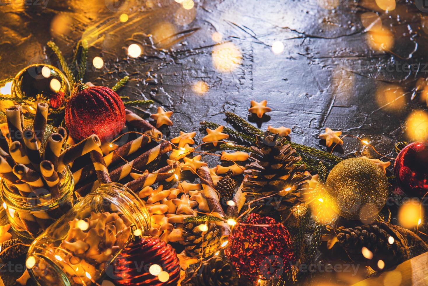 palle di decorazione natalizia con biscotti e pasticcini su sfondo nero bokeh astratto con spazio copia e luci a led decorative. buon natale e anno nuovo. biglietto d'auguri. foto