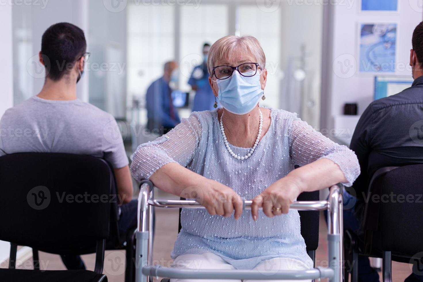 donna anziana disabile con maschera facciale e deambulatore che guarda l'obbiettivo foto