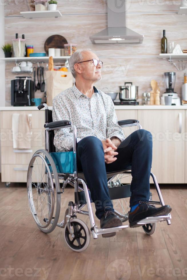 uomo anziano disabile seduto in sedia a rotelle foto