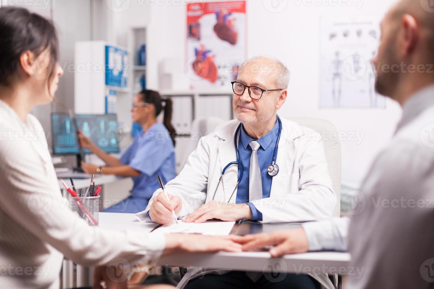 medico anziano che scrive appunti negli appunti foto