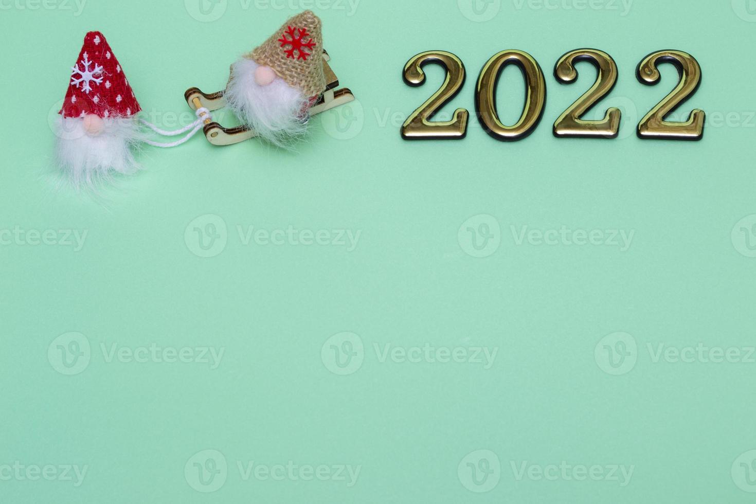 gnomi di natale sulla slitta con numeri d'oro 2022 su sfondo blu con posto per il testo foto