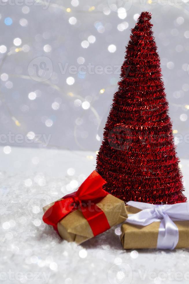 albero di natale con doni sulla neve su uno sfondo di luci luminose bokeh. concetto minimo di cartolina, biglietto d'invito. chiudi con copia spazio foto