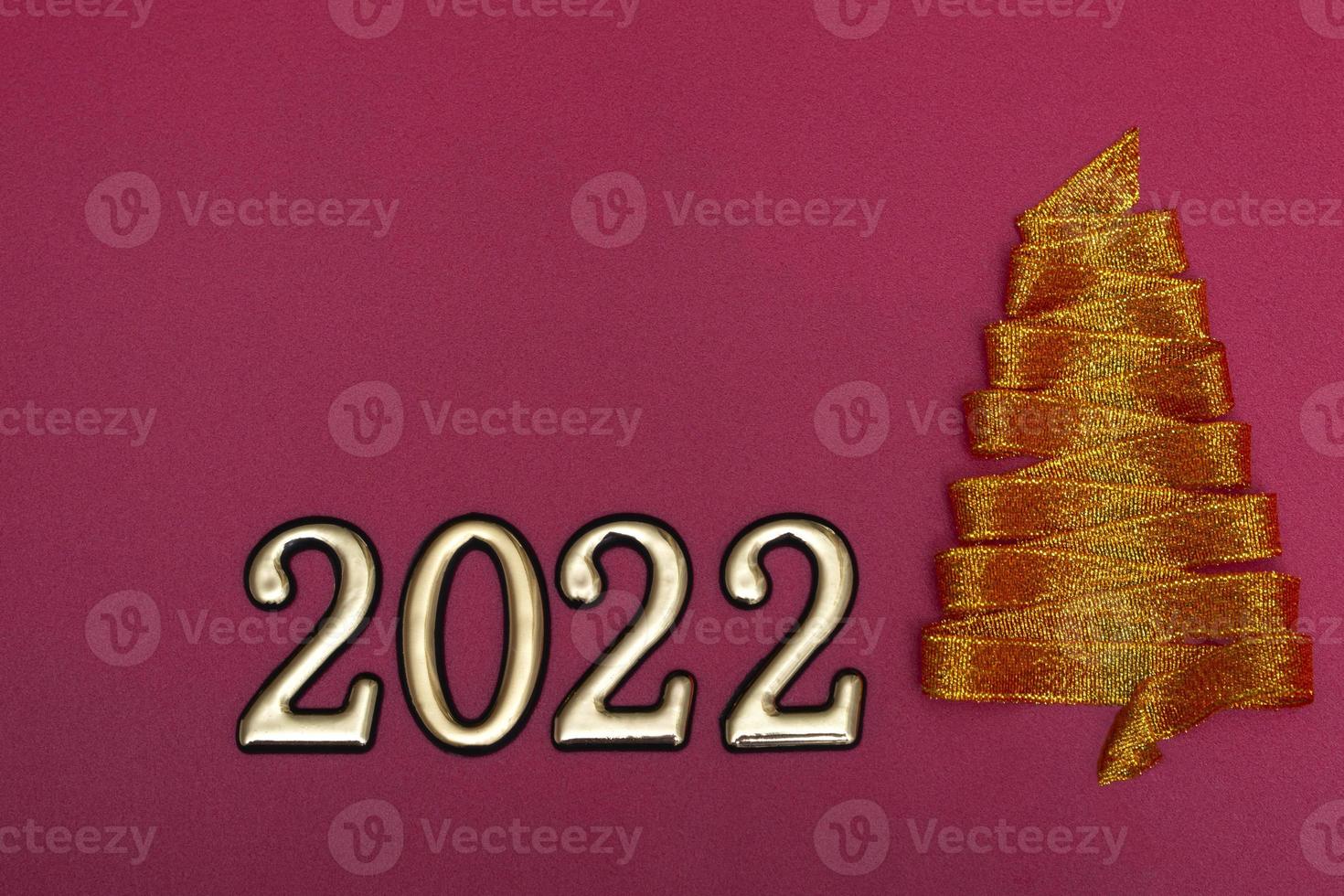 concetto di natale. albero di natale d'oro fatto di nastri e numeri d'oro su sfondo rosa. modello per cartoline, imballaggio. foto