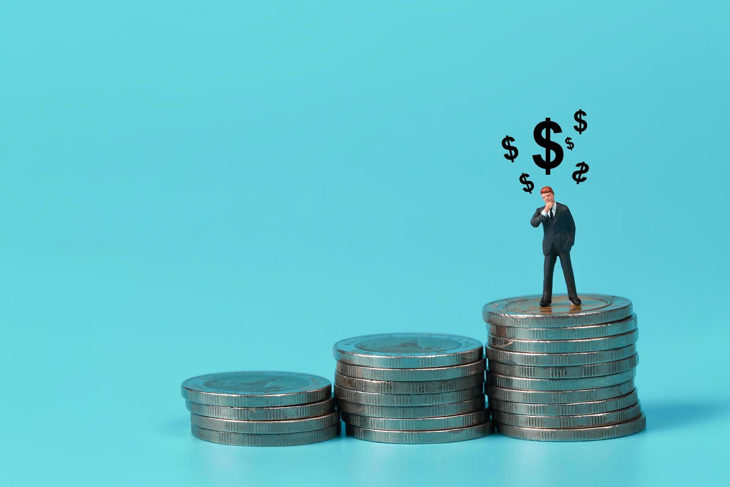 uomo d'affari in piedi sul podio di impilamento di monete con il simbolo del dollaro utilizzato come sfondo foto